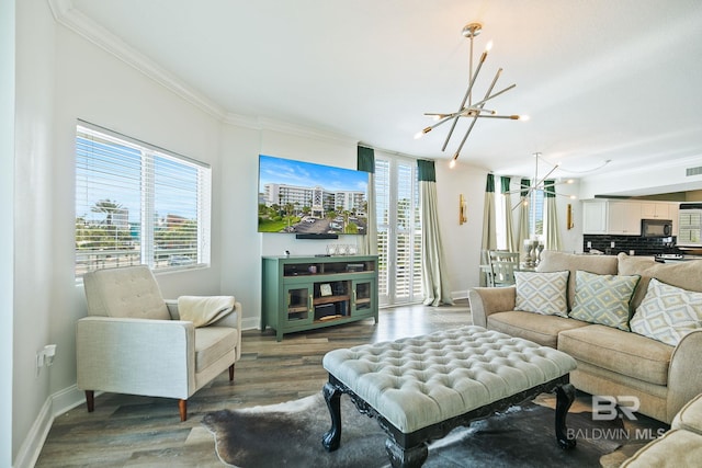 living room with plenty of natural light, crown molding, a chandelier, and hardwood / wood-style flooring