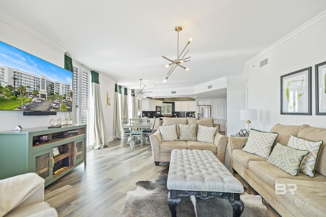 living room with ornamental molding, light wood-type flooring, and an inviting chandelier