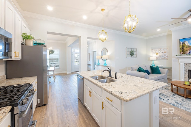 kitchen featuring crown molding, a kitchen island with sink, white cabinetry, light wood-type flooring, and sink