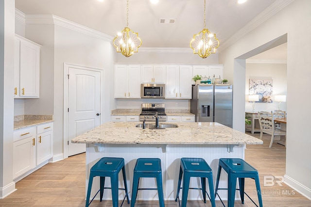 kitchen featuring an island with sink, light hardwood / wood-style floors, pendant lighting, and stainless steel appliances