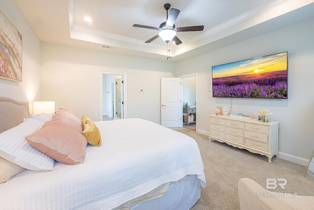 bedroom featuring a tray ceiling, ceiling fan, ensuite bath, and light colored carpet