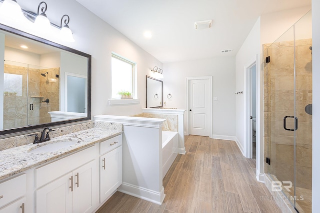 bathroom with independent shower and bath, hardwood / wood-style floors, and large vanity