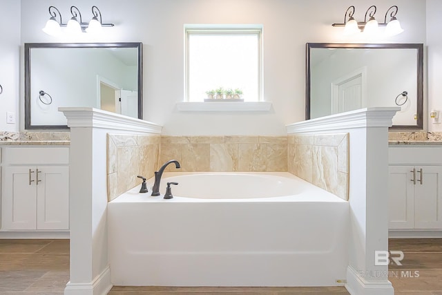 bathroom with a bath, wood-type flooring, and vanity with extensive cabinet space