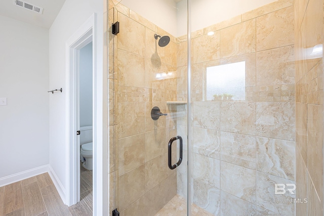 bathroom featuring walk in shower, toilet, and hardwood / wood-style floors