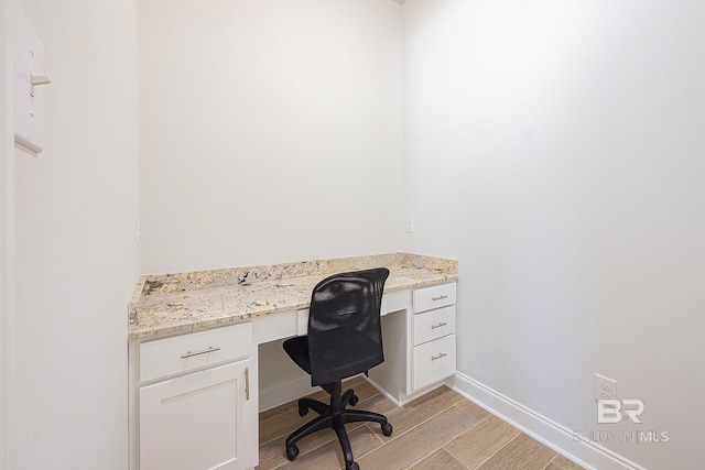 unfurnished office featuring built in desk and light hardwood / wood-style flooring