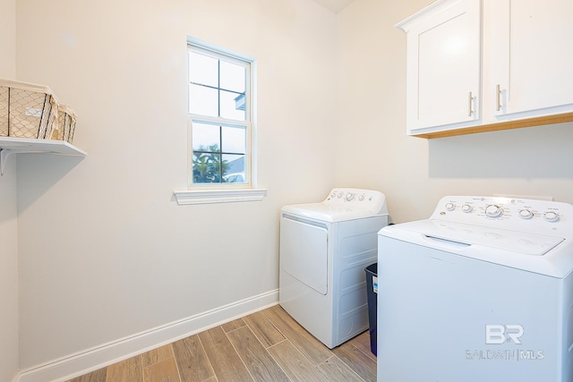 laundry room with separate washer and dryer, light hardwood / wood-style flooring, and cabinets