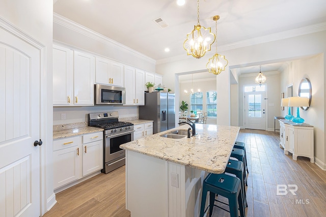 kitchen featuring light hardwood / wood-style floors, appliances with stainless steel finishes, white cabinets, a kitchen island with sink, and sink