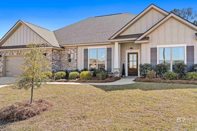 view of front of house featuring roof with shingles, an attached garage, a front lawn, board and batten siding, and brick siding