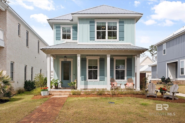 view of front of house with board and batten siding, covered porch, metal roof, and a front lawn