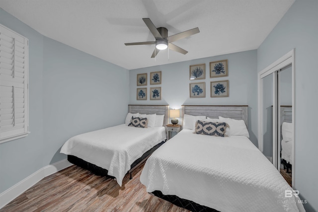 bedroom featuring ceiling fan, a closet, baseboards, and wood finished floors