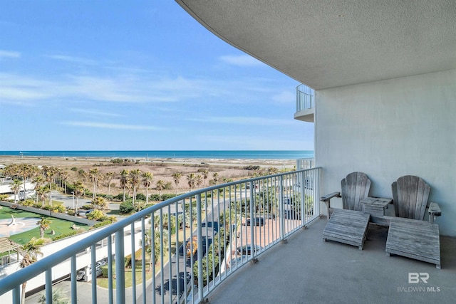 balcony featuring a view of the beach and a water view