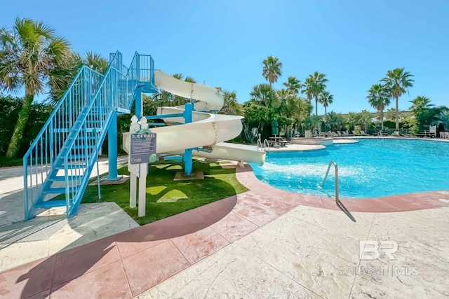 community pool with a patio and a water slide