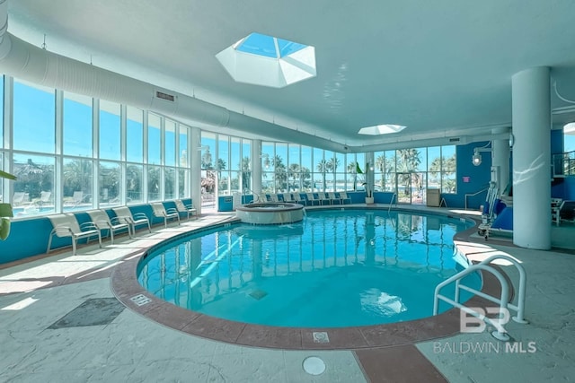 view of pool with a skylight and a pool with connected hot tub