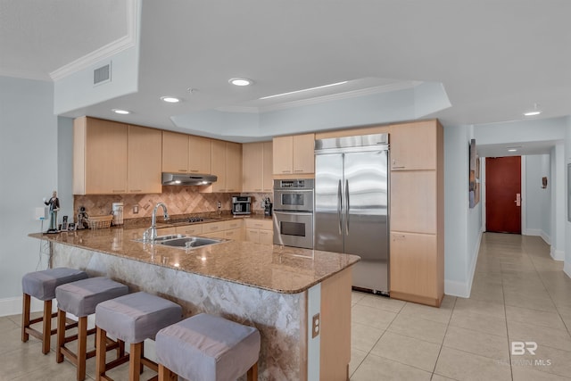 kitchen featuring visible vents, a peninsula, stainless steel appliances, under cabinet range hood, and backsplash