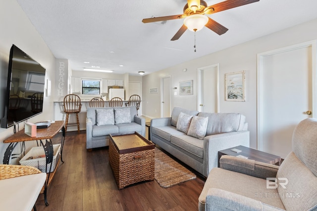 living area featuring ceiling fan, baseboards, and dark wood-style floors