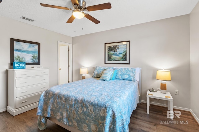 bedroom featuring visible vents, baseboards, wood finished floors, a textured ceiling, and a ceiling fan