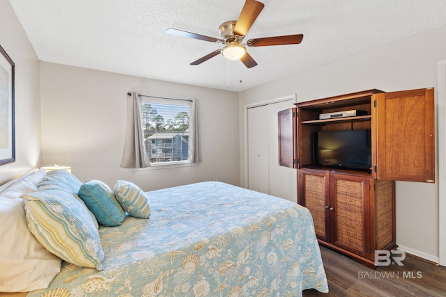 bedroom with a textured ceiling, wood finished floors, a closet, baseboards, and ceiling fan