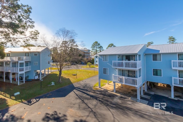 beach home featuring a residential view, driveway, metal roof, and a front yard