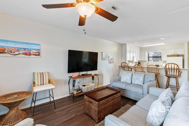 living area with visible vents, ceiling fan, baseboards, and wood finished floors