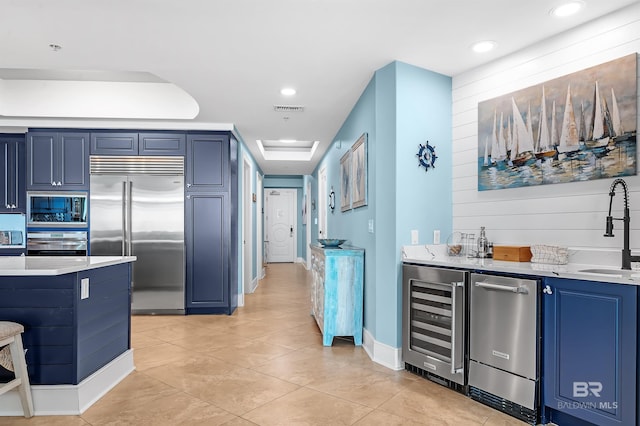 kitchen with blue cabinets, beverage cooler, light countertops, and built in appliances