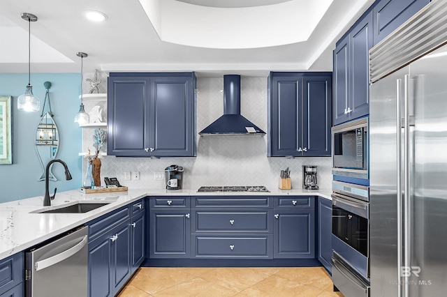 kitchen with wall chimney exhaust hood, built in appliances, blue cabinetry, open shelves, and a sink