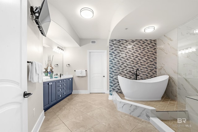 full bathroom featuring baseboards, visible vents, a soaking tub, vanity, and tile walls