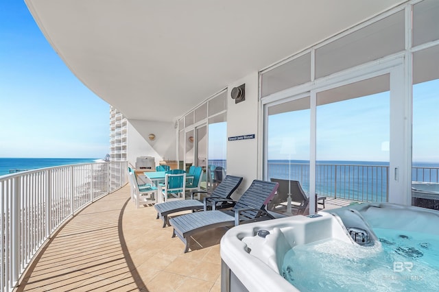 balcony featuring a water view, a hot tub, and outdoor dining area