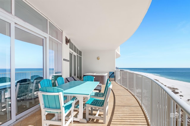 balcony with outdoor dining space, a water view, and a view of the beach