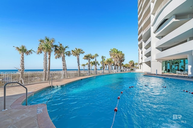 community pool with a water view and fence