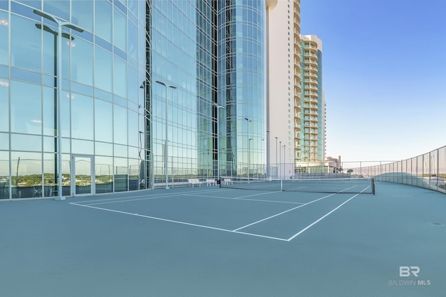 view of tennis court featuring a city view and fence