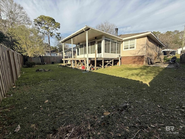 back of property with a sunroom, a fenced backyard, and a lawn