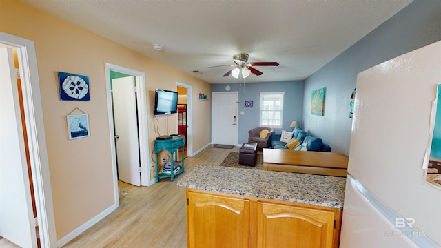 kitchen featuring light wood-type flooring, ceiling fan, white fridge, and a textured ceiling