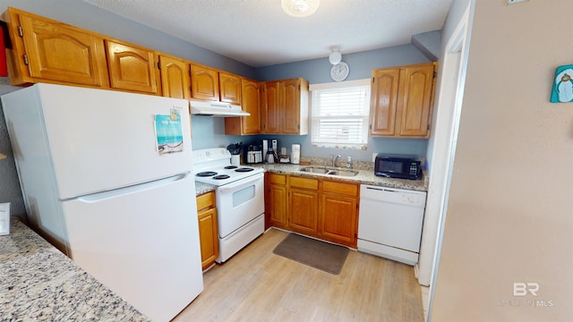 kitchen with light wood-type flooring, sink, white appliances, a textured ceiling, and light stone countertops