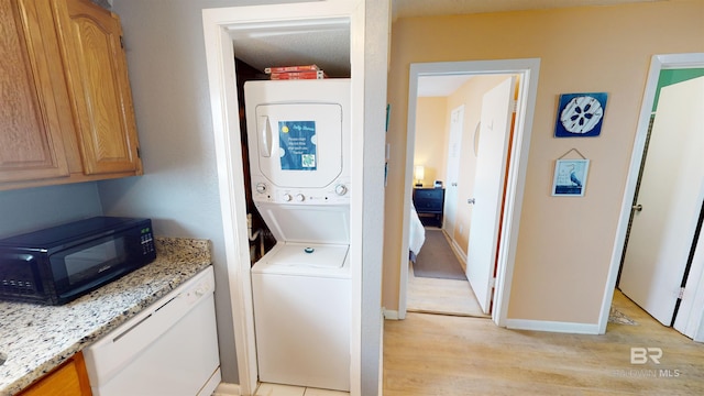 laundry area with light hardwood / wood-style floors, stacked washer / dryer, and a textured ceiling