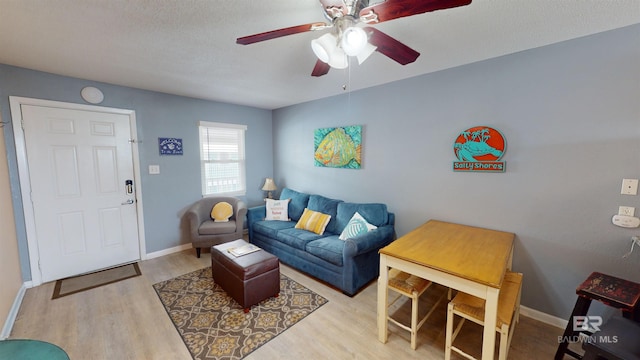 living room featuring light hardwood / wood-style floors, ceiling fan, and a textured ceiling