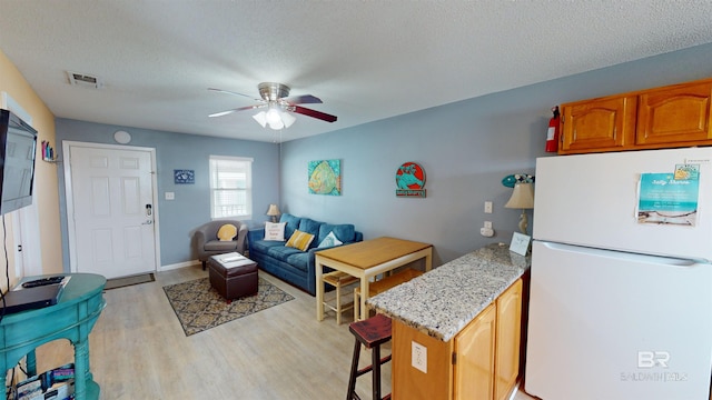 interior space featuring a textured ceiling, light hardwood / wood-style floors, and ceiling fan