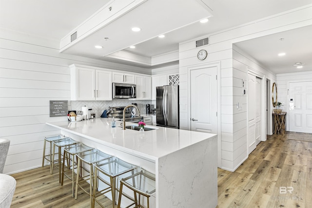 453 Dune Dr Unit 404, Gulf Shores, AL 36542 - kitchen featuring stainless steel appliances, a breakfast bar area, a peninsula, light wood finished floors, and ornamental molding