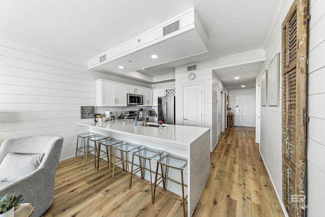 453 Dune Dr Unit 404, Gulf Shores, AL 36542 - kitchen featuring appliances with stainless steel finishes, crown molding, a peninsula, a kitchen bar, and light countertops