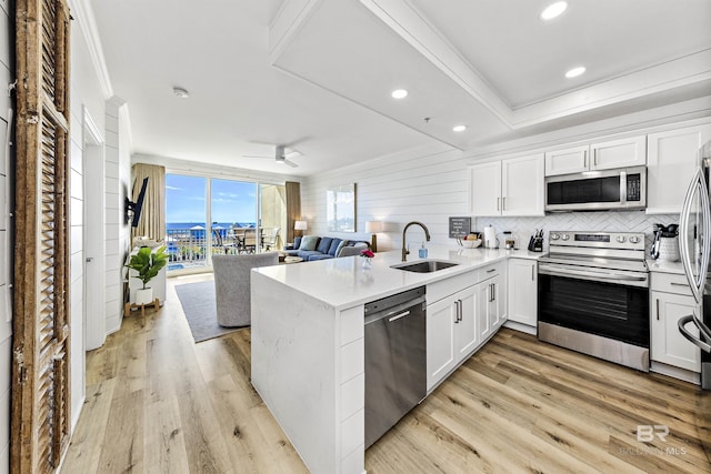 453 Dune Dr Unit 404, Gulf Shores, AL 36542 - kitchen featuring appliances with stainless steel finishes, a peninsula, white cabinets, backsplash, and ornamental molding