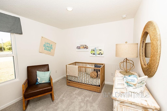 bedroom with light carpet, a textured ceiling, a nursery area, and baseboards