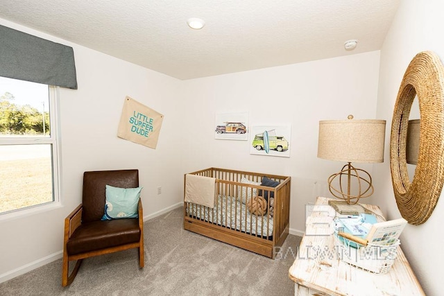 bedroom featuring light carpet, a textured ceiling, a nursery area, and baseboards