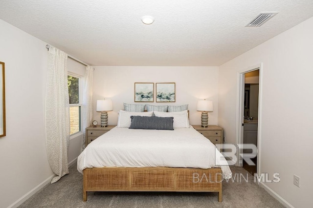 carpeted bedroom featuring baseboards, visible vents, and a textured ceiling