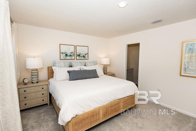 bedroom featuring a textured ceiling, carpet, visible vents, and baseboards