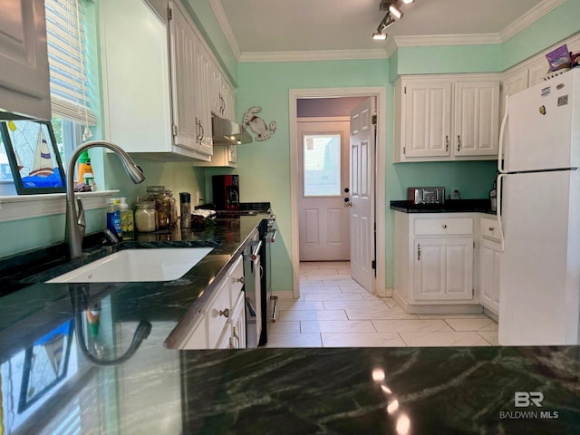 kitchen with ornamental molding, under cabinet range hood, a sink, freestanding refrigerator, and white cabinets