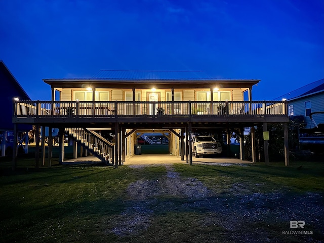 back of house at twilight featuring a carport, stairway, a yard, and driveway