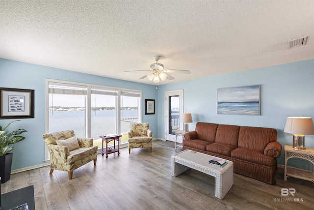 1872 W Beach Blvd Unit 206, Gulf Shores, AL 36542 - living room featuring wood finished floors, a textured ceiling, ceiling fan, baseboards, and a water view