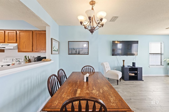 1872 W Beach Blvd Unit 206, Gulf Shores, AL 36542 - dining space featuring light wood-style flooring, a chandelier, a textured ceiling, and baseboards