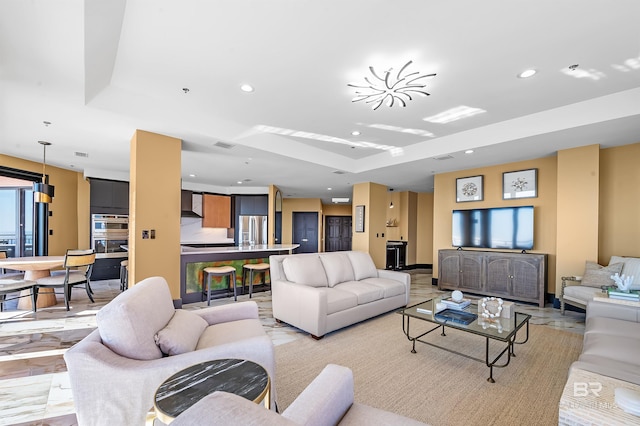 living room with recessed lighting, visible vents, and a tray ceiling