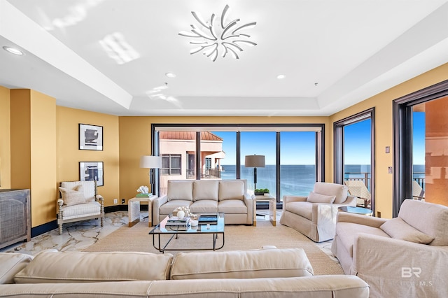 living area with a water view, baseboards, a tray ceiling, and recessed lighting