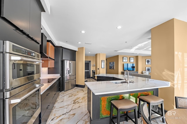 kitchen with stainless steel appliances, a spacious island, a sink, marble finish floor, and modern cabinets